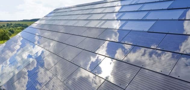 Multiple longer buildings on a green field with solar panels on it